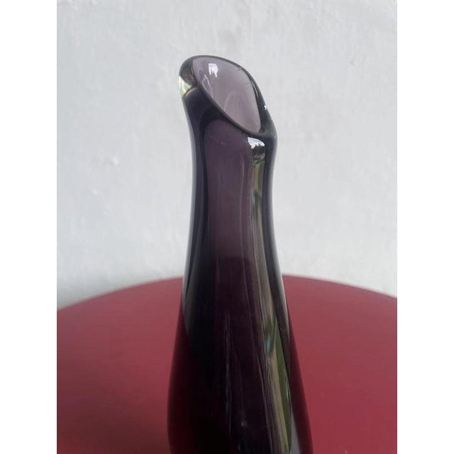 The piece features a deep purple or amethyst color submerged within clear glass, creating a striking visual effect through...