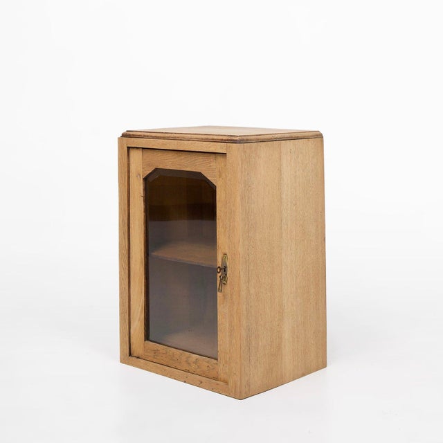 A charming French table cabinet from around 1900, crafted in solid wood with a warm natural finish and a single glass-...