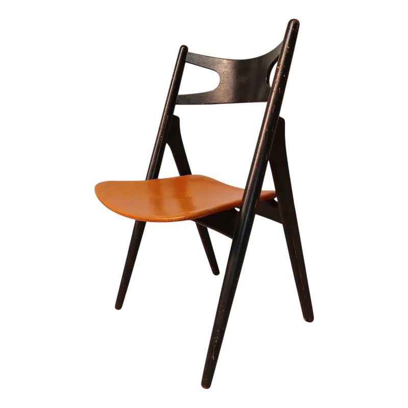 A black folding chair with a brown leather seat