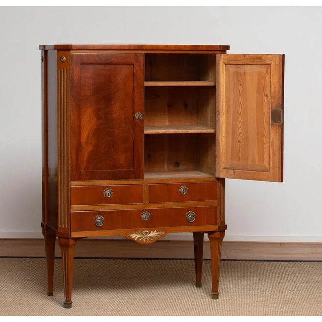 Elegant Louis XVI style cabinet from France, crafted in mahogany veneer with refined brass inlays. The cabinet features...