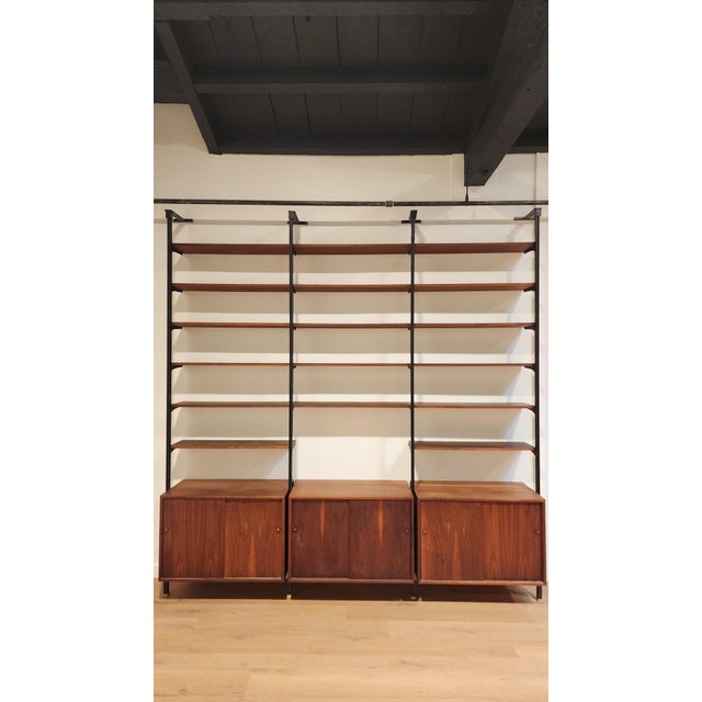 Striking mid-century modern wall unit in the style of George Nelson, featuring a versatile modular shelving system with...