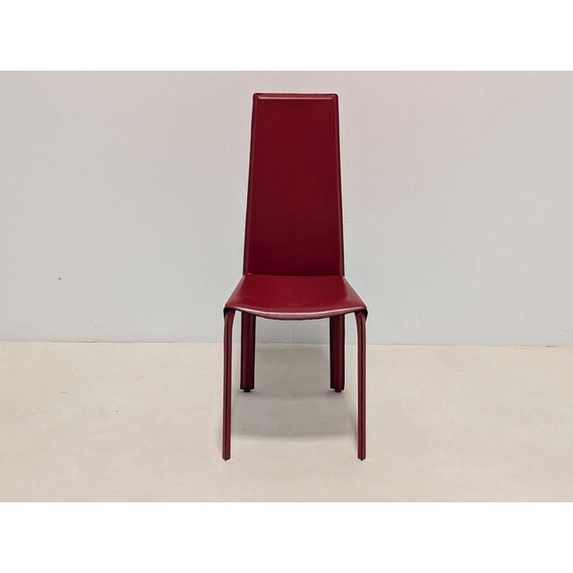Elegant kristalia designer dining chairs, upholstered entirely in a rich deep-red leather. The chairs feature a...
