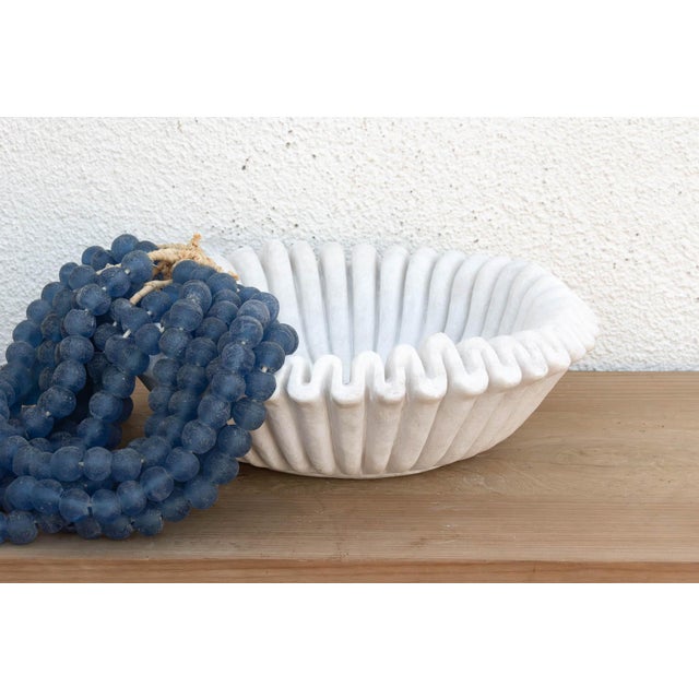 Carved from a single block of pristine white marble, the vessel has been meticulously hand-chiseled to create a continuous...