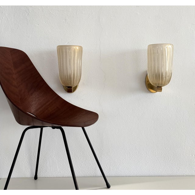 Beautiful set of two large wall lamps made of strong brass base and light wavy murano glasses in light creamy color with...