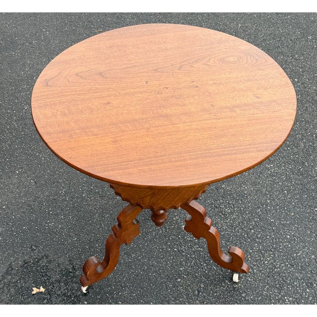 Antique 19th Century walnut Victorian table. Round wood top supported by a central pedestal that leads to a scalloped-edge...