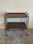 This two-tier folding bar cart features rich wood surfaces supported by a sleek metallic frame on smooth-rolling casters....