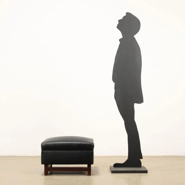 Pouf, foam padding, imitation leather covering, wooden legs. This piece is attributed to the mentioned designer/maker. It...