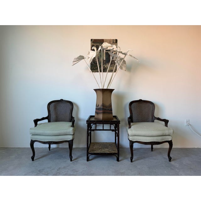 Elegant vintage two-tier side table by Palecek featuring a beautifully carved faux bamboo frame with woven rattan...