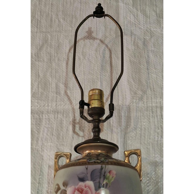 Vintage porcelain table lamp featuring a graceful urn-form body beautifully decorated with hand-painted pink roses,...