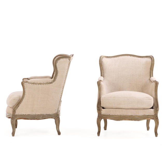 A handsome pair of French painted bergère chairs dating to circa 1900, featuring gracefully carved frames with serpentine...