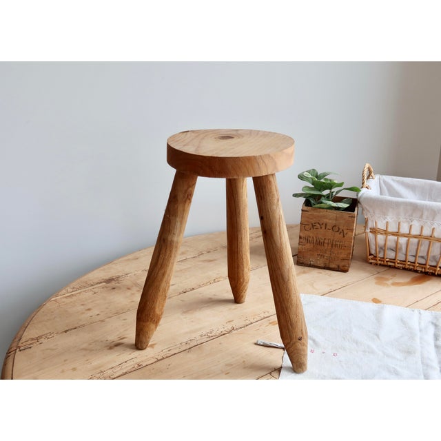 This raw wood tripod stool charms with its simple and authentic form, featuring a thick, round seat and three slightly...