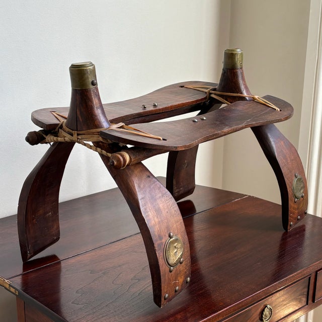 A vintage mid-20th century Middle Eastern camel saddle with Pharaonic decorative brass accents. A gorgeous decorative...