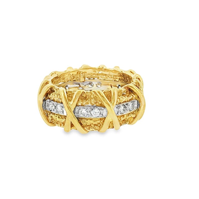 A striking 18k gold band ring from the 1970s. This piece features a textured design with crisscrossing gold bands. The...