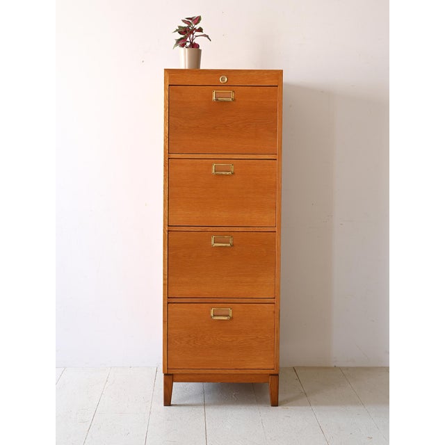 Oak file cabinet with gold metal handles. Featuring four spacious drawers, this chest of drawers provides abundant space...