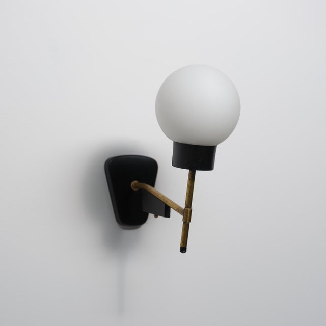 This 1950s Italian wall sconce combines a compact sculptural form with refined materials. The design features a black-...