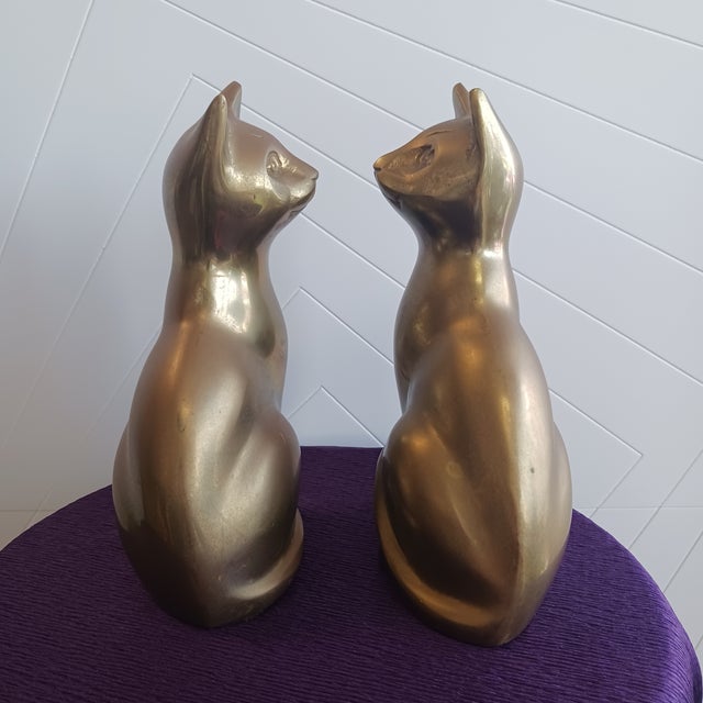 ​A striking and exceptionally substantial pair of vintage solid brass sitting cat sculptures. Reaching nearly 9 inches in...