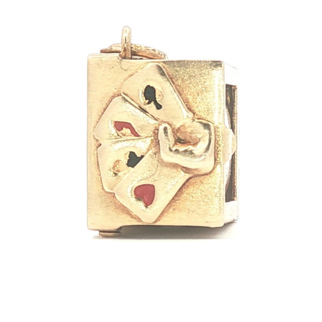A vintage 14k yellow gold charm. This unique piece features a miniature playing card encased within a rectangular frame....