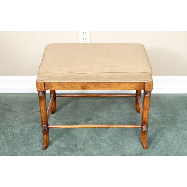 A vintage vanity foot stool or ottoman with a wooden frame with faux bamboo turned legs and a beige upholstered padded...