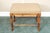 A vintage vanity foot stool or ottoman with a wooden frame with faux bamboo turned legs and a beige upholstered padded...