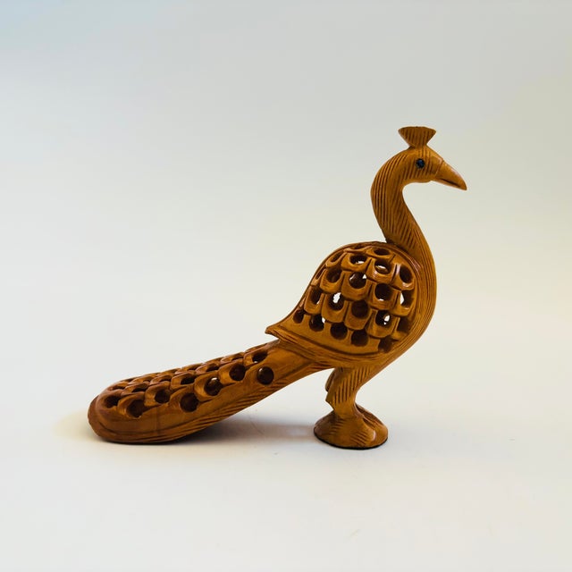 A small vintage carved wood peacock figurine. Measures 4.5"W x 1.5"D x 1"H
