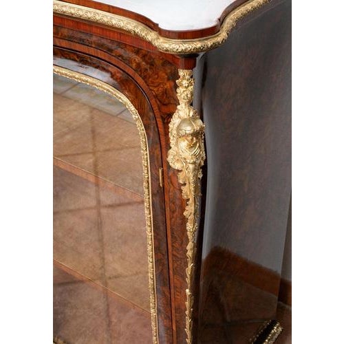 Victorian showcase in walnut root with expertly chiseled gilded bronze elements. The front elevation is characterized by...