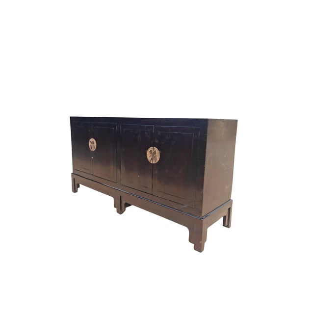 This early 20th century sideboard features a sleek, dark brown lacquer finish highlighting its minimalistic silhouette....