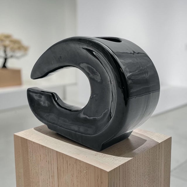 This sculptural ceramic ikebana vase features a modern crescent form designed to support asymmetrical floral arrangements....