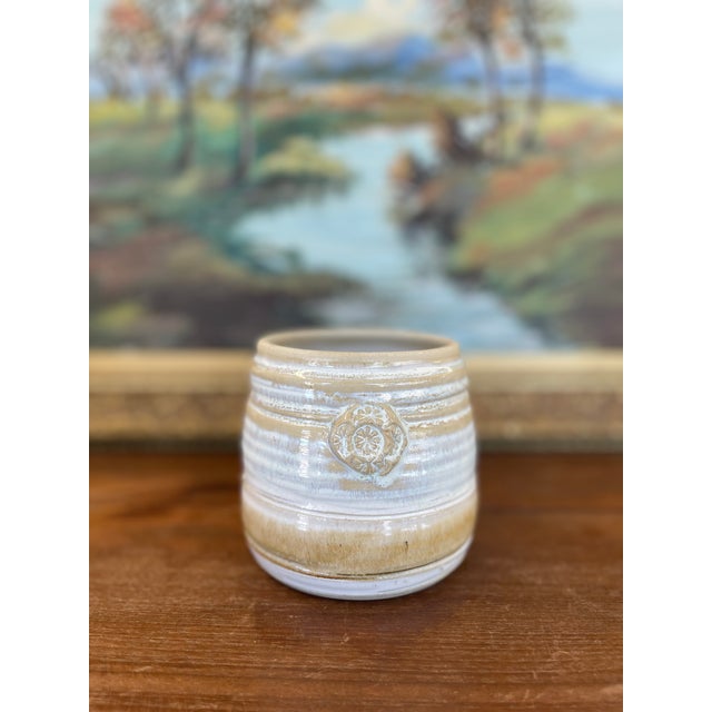 Hand-thrown studio pottery vessel signed by Freeburg, featuring a warm tan and ivory glaze with subtle variegation and...