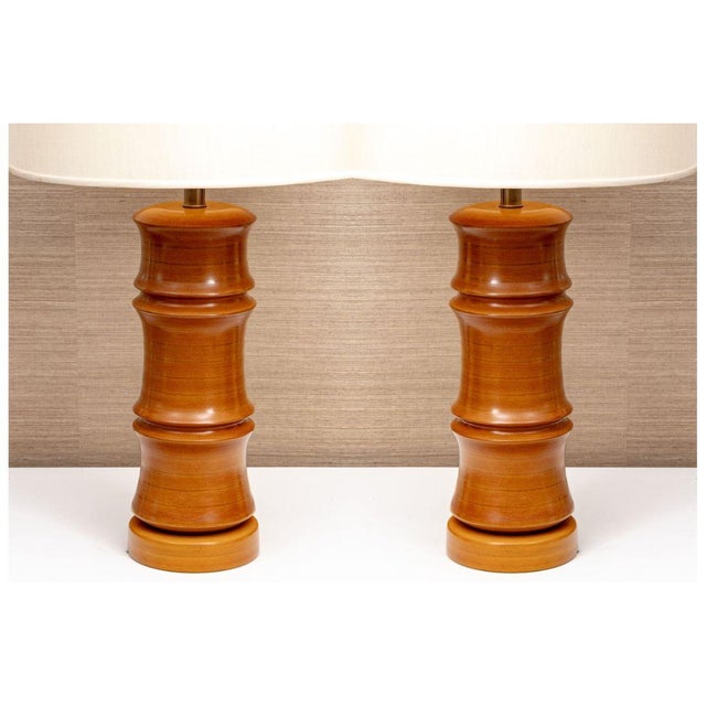 A pair of vintage table lamps hand carved in warm toned wood with sculptural bamboo form bodies. Each lamp features a...