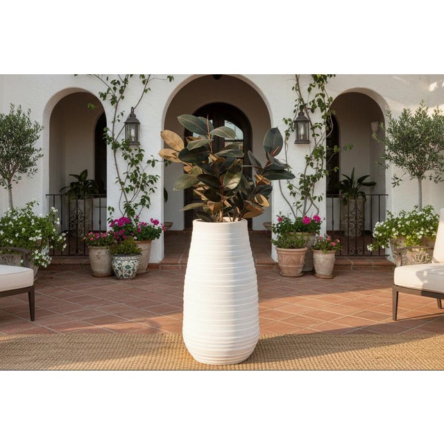 This elegant large terracota vessel emphasizes verticality and texture. Shaped like a tall, slender barrel it stands an...