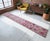 This authentic 1960s Southeastern Anatolian runner rug features a vibrant tribal geometric design in magenta pinks and...