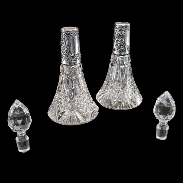 This is a pair of small antique scent bottles. An English, cut glass perfume decanter with Sterling silver collars, dating...