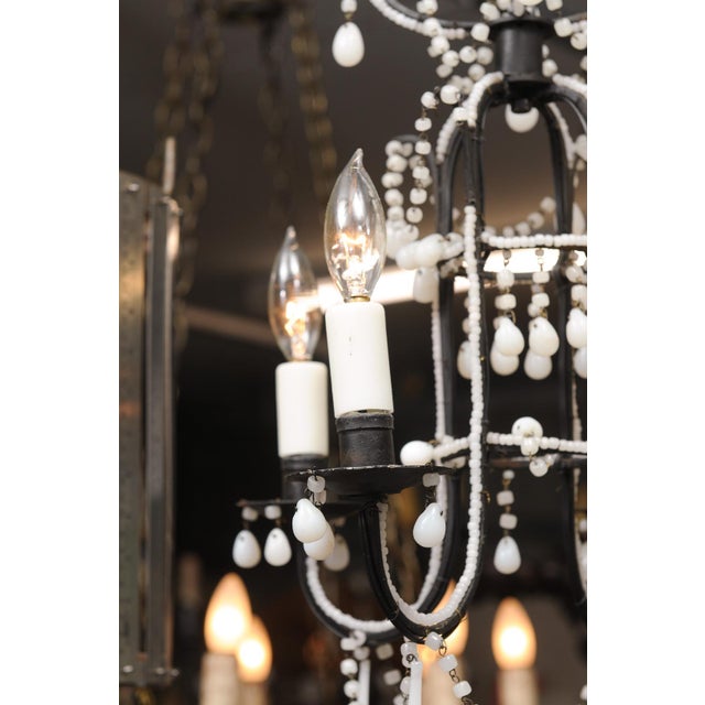 A charming 4-light hand wrought iron Italian chandelier with opaline glass beaded accents and drops. This chandelier has...