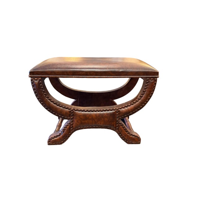 A pair of vintage curule-style leather footstools featuring padded tops upholstered in a four-quadrant, geometric leather...