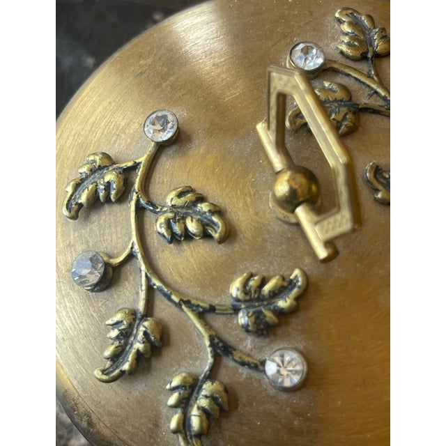 Vintage Round Gold Tone Box. Top features Leaf Motif with Diamond Accents. Ruby Red Velvet inside the box.