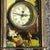 This charming timepiece features a beautifully detailed rectangular brass case with a classic patina finish. The standout...