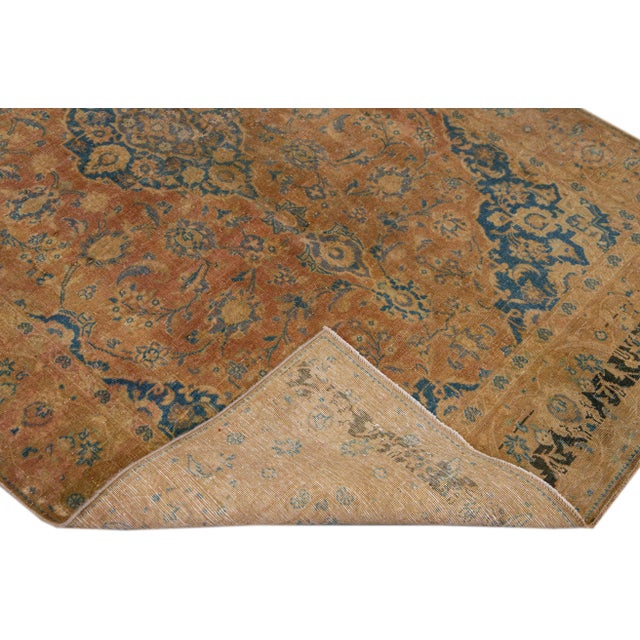 Beautiful vintage Persian distressed hand-knotted wool rug with a tan color field. This piece has blue accents in an all-...