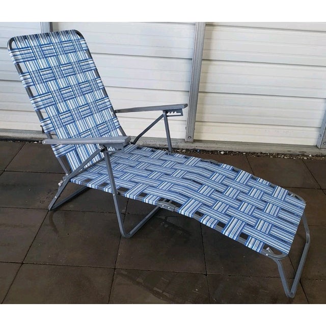 Relive the golden era of backyard barbecues and beach days with this iconic vintage webbed aluminum folding lounge chair....
