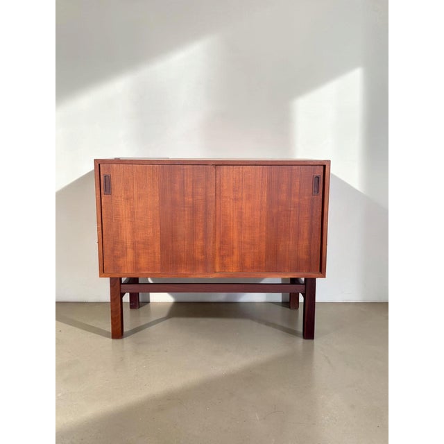 A truly beautiful piece: this Danish teak sideboard features two sliding doors and built-in storage. On one side, there is...