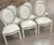 A chic set of 6 Louis XVI style balloon back dining chairs, recently upholstered in white leather with black welting. The...