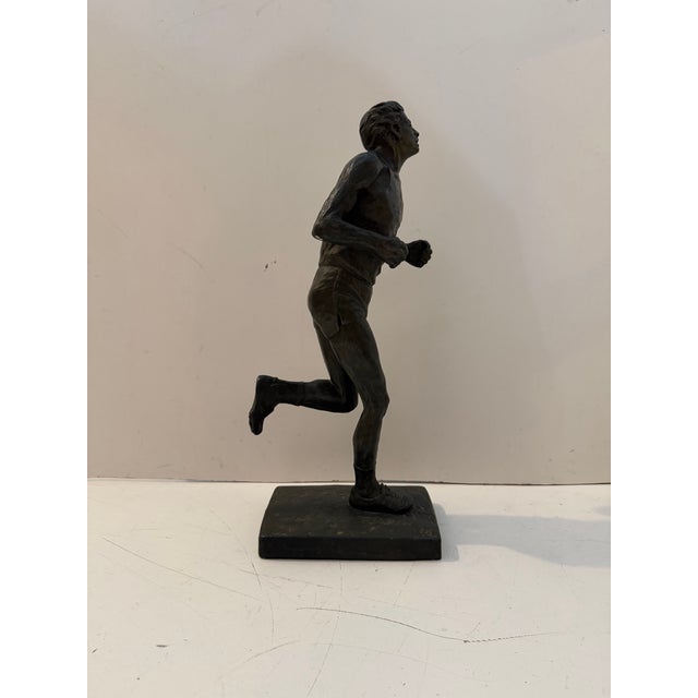 Dynamic vintage figurative sculpture depicting a long-distance runner in mid-stride, produced by Austin Productions in...