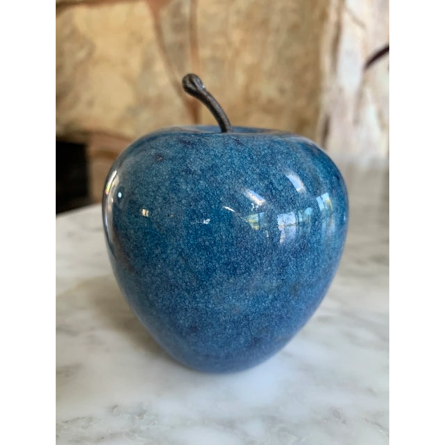 Bright blue marble apple paper weight with a stem.