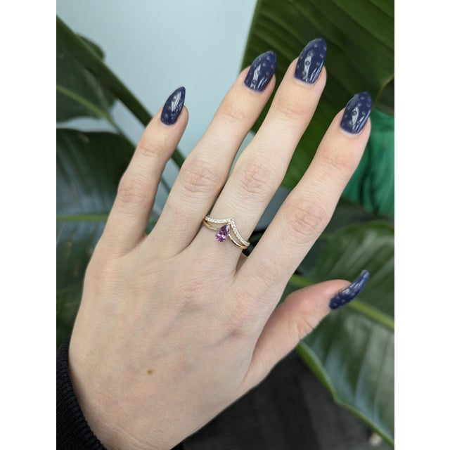 Pink Sapphire Ring with Natural Diamond Accents Set in solid 14k gold, this elegant design features a 7×4mm pink sapphire...