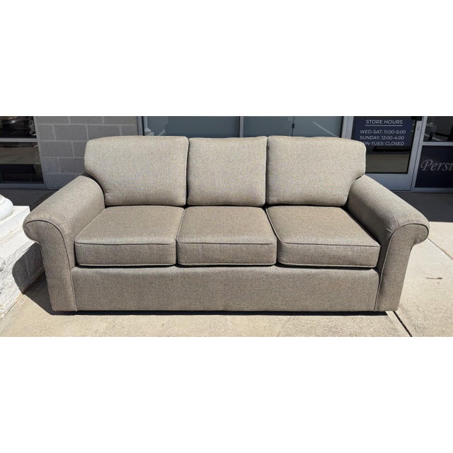 This Hickory-Fry sofa features light brown upholstery, three loose seat cushions, fixed back cushions, and gently rolled...