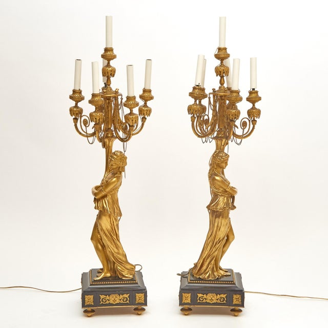 An impressive and highly decorative pair of 19th-century gilded bronze ormolu six-light figural candelabra, showcasing...