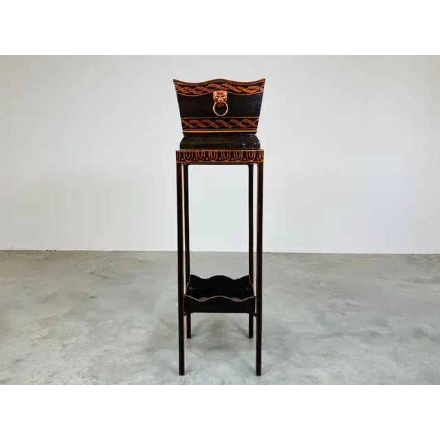 An elegant interior plant stand in the regency style having Tole Metal frame with brass lion face front and back accents...