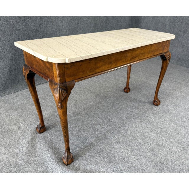 This 19th century foyer table features a rectangular cream marble top with soft veining and rounded corners. The carved...