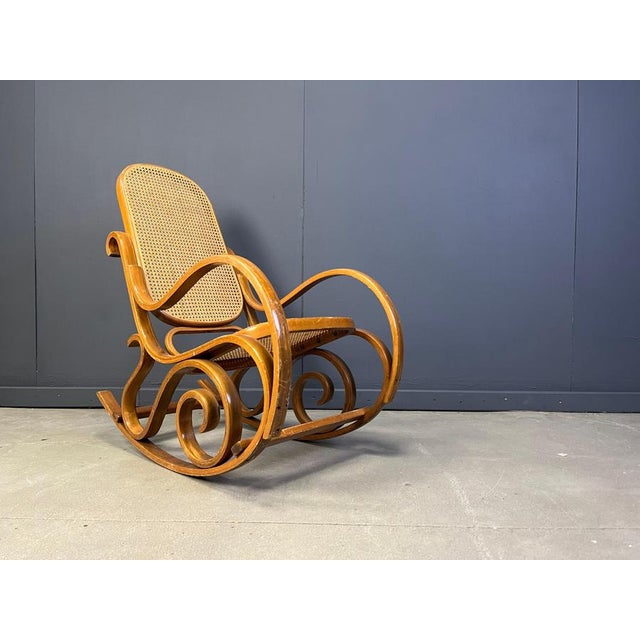Mid century dark brown wooden and cane webbing rocking chair. These thonet style rocking chair has a very elegant curling...