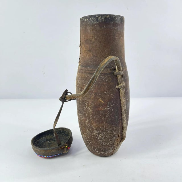 Milk container with a removable beaded lid. Has an animal hide strap to carry it. Hand-carved wooden milk container made...
