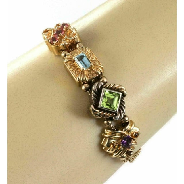 This vintage bracelet features four charms on a double chain, with each charm representing different multicolor gems set...